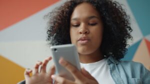 Young woman looking at her smartphone with colorful background